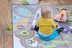 Kleinkind mit Spielzeug auf einem Spielteppich